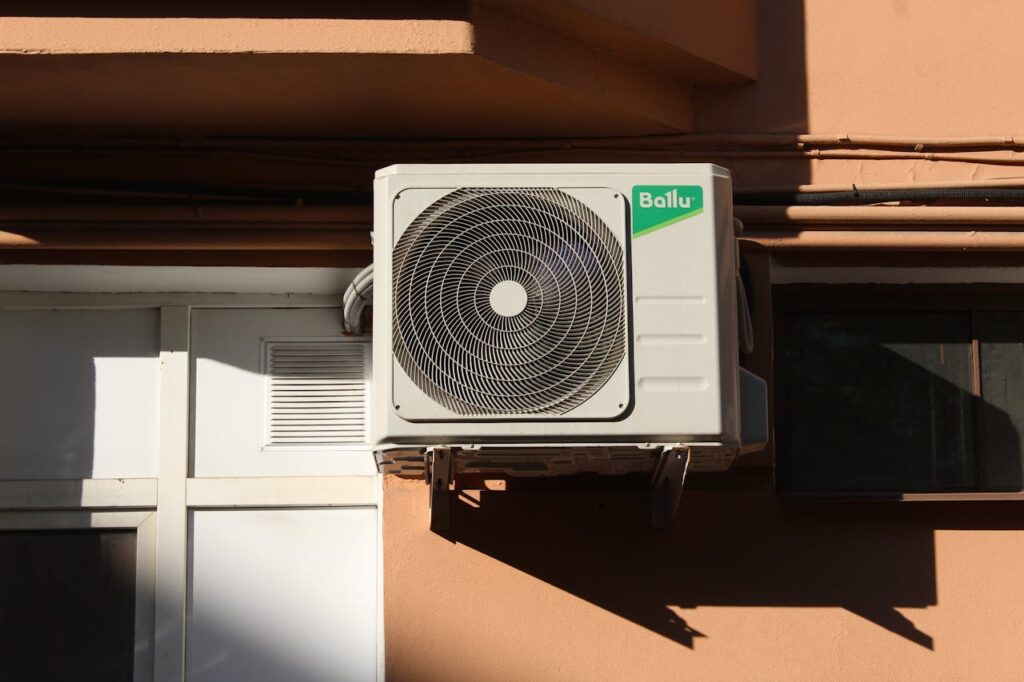 The Art of Drawing Readers In: Your attractive post title goes here A Ballu air conditioner condenser unit mounted on a building exterior, showcasing modern HVAC technology.