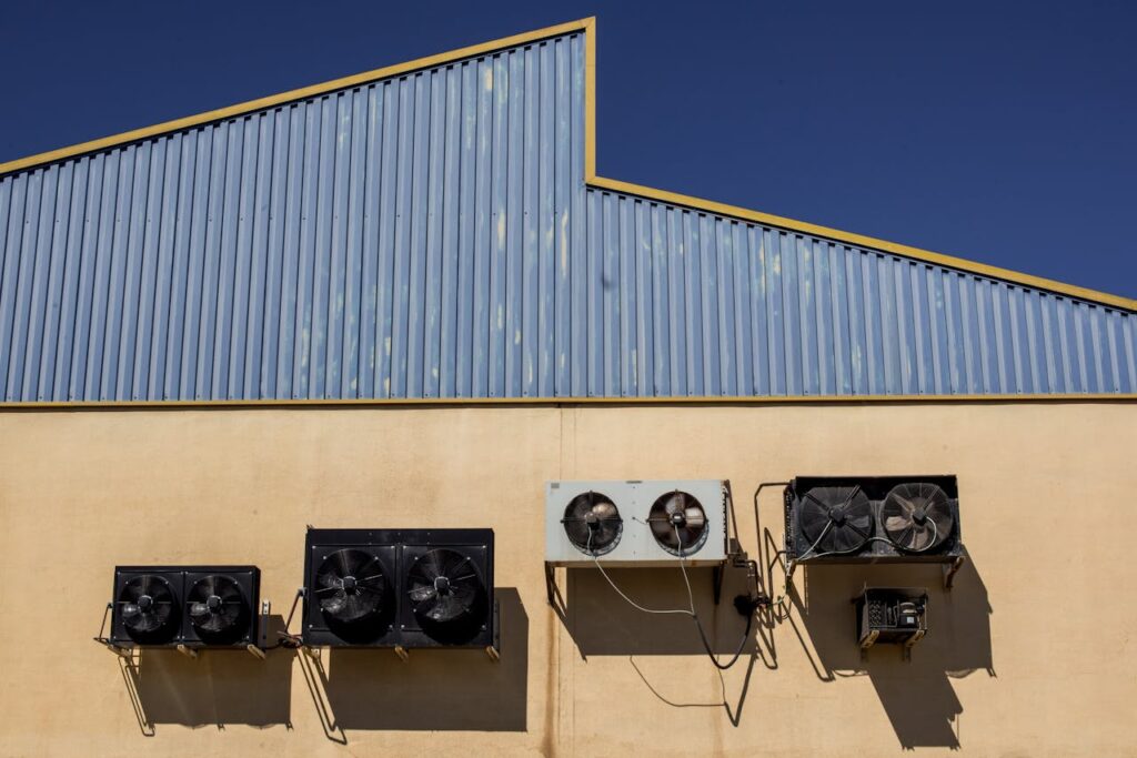 Mastering the First Impression: Your intriguing post title goes here Exterior view of industrial air conditioning units mounted on a warehouse wall under clear blue sky.